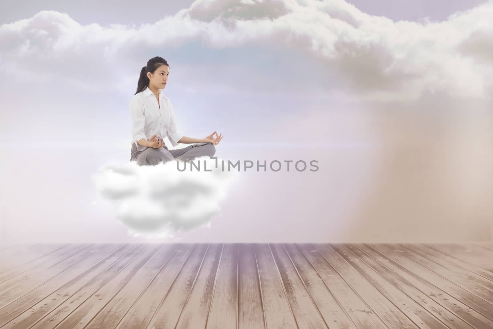 Businesswoman sitting in lotus pose against clouds in a room