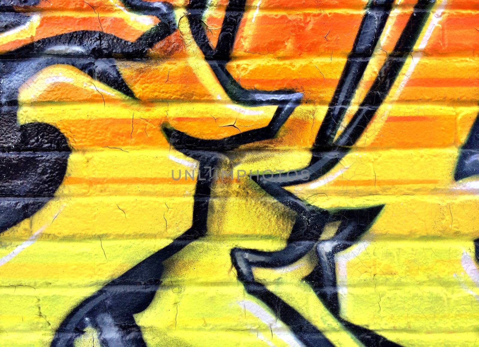 Bright black and yellow graffiti detail on a brick wall.