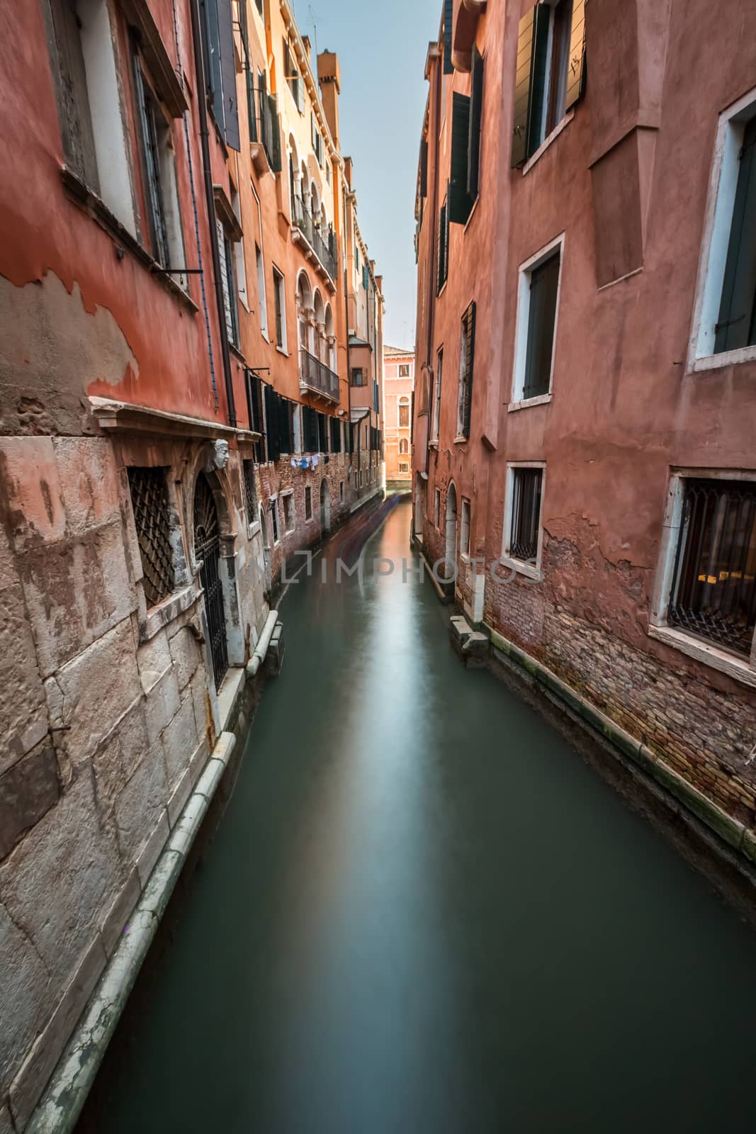 Narrow Canal Among Old Colorful Brick Houses in Venice, Italy