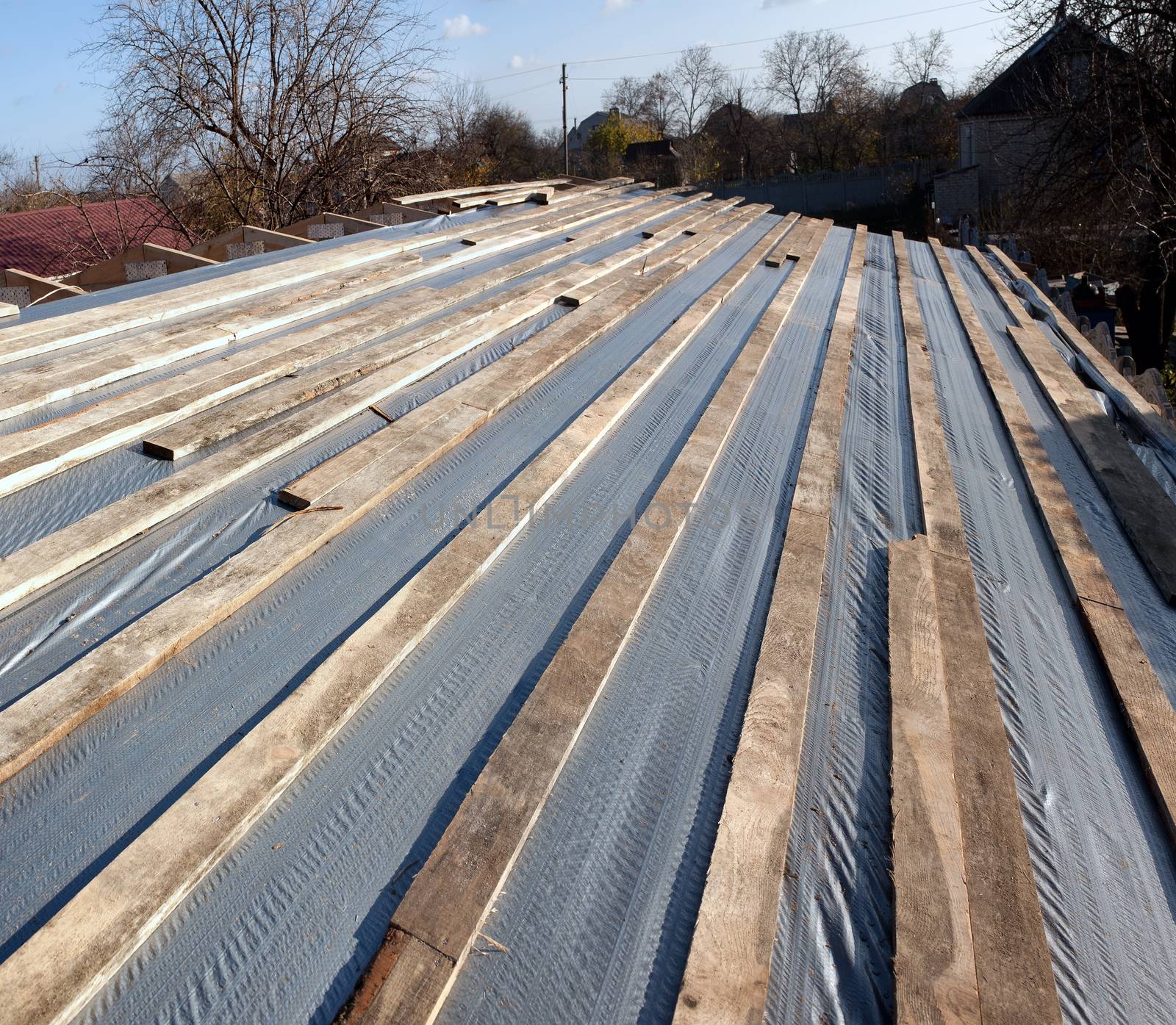 
General view of the installation of protective construction material - hydraulic barrier in the construction of the roof of a one-storey building