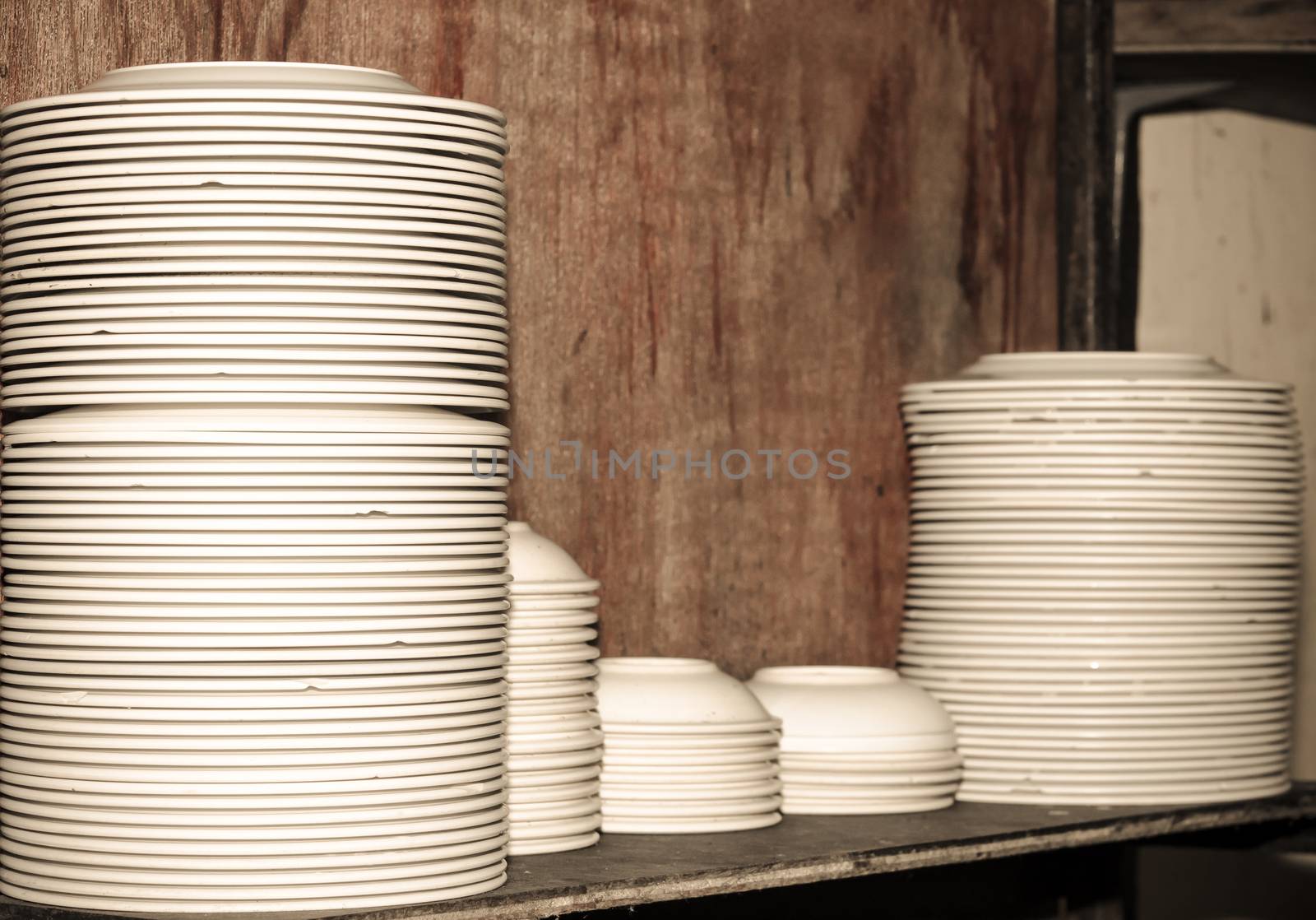 The white plastic plates stacked on wood.