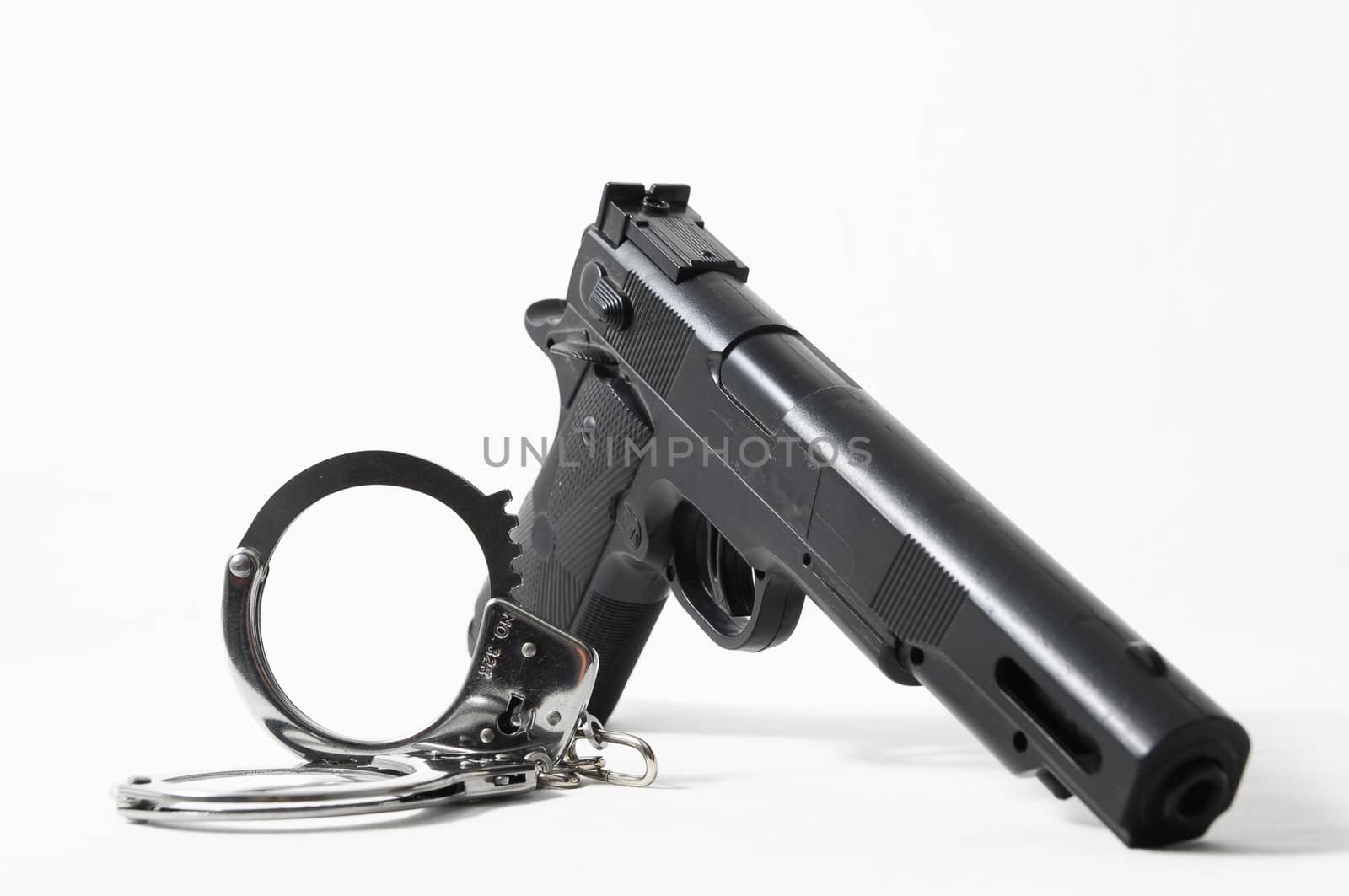 Weapon Crime Concept Gun and Handcuffs on a White Background