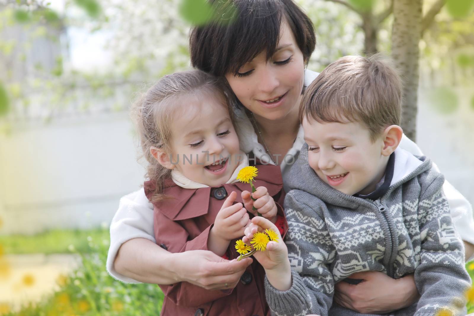 Happy mother and two children admiring spring garden