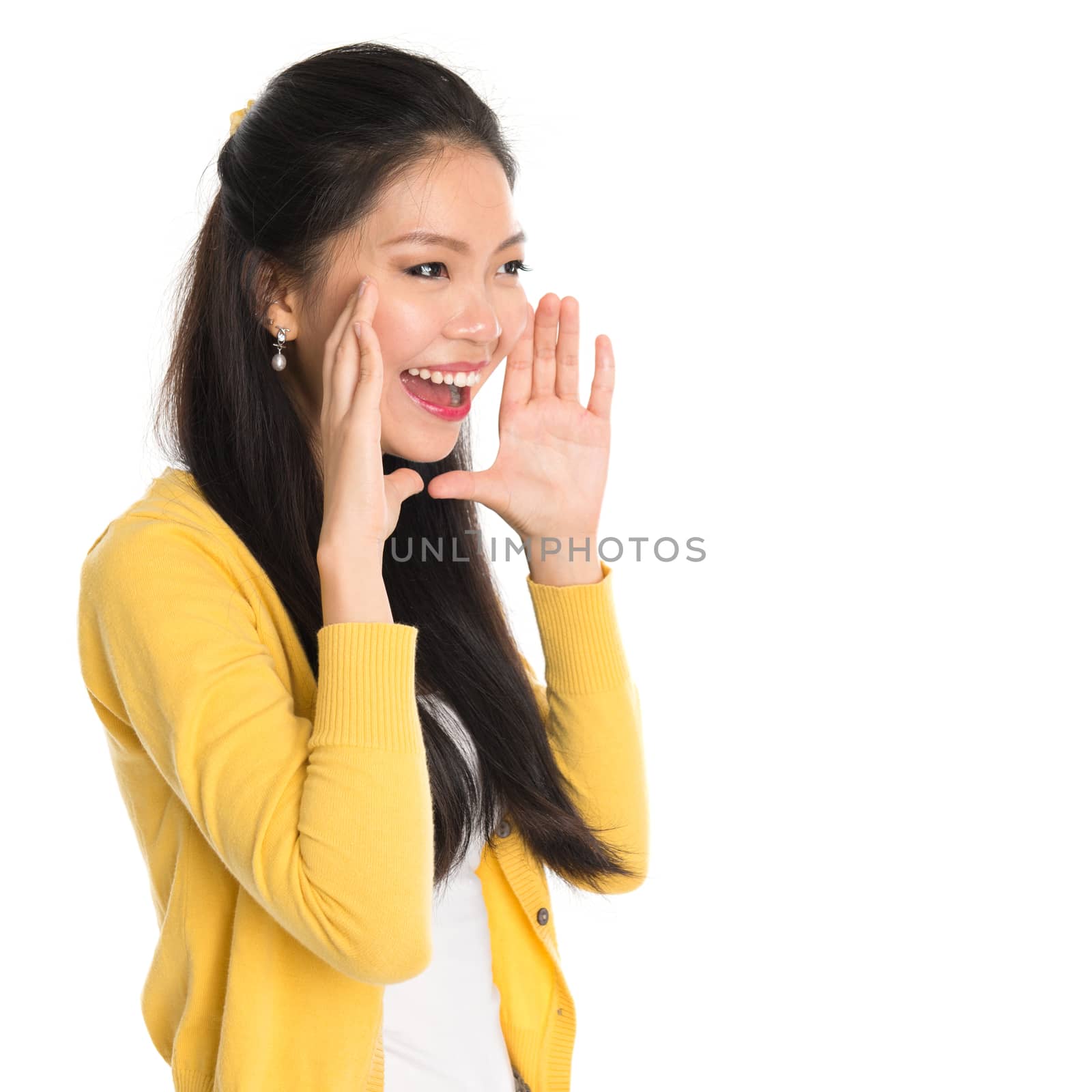 Young Asian girl shouting loud, hands next to the mouth, isolated on white background