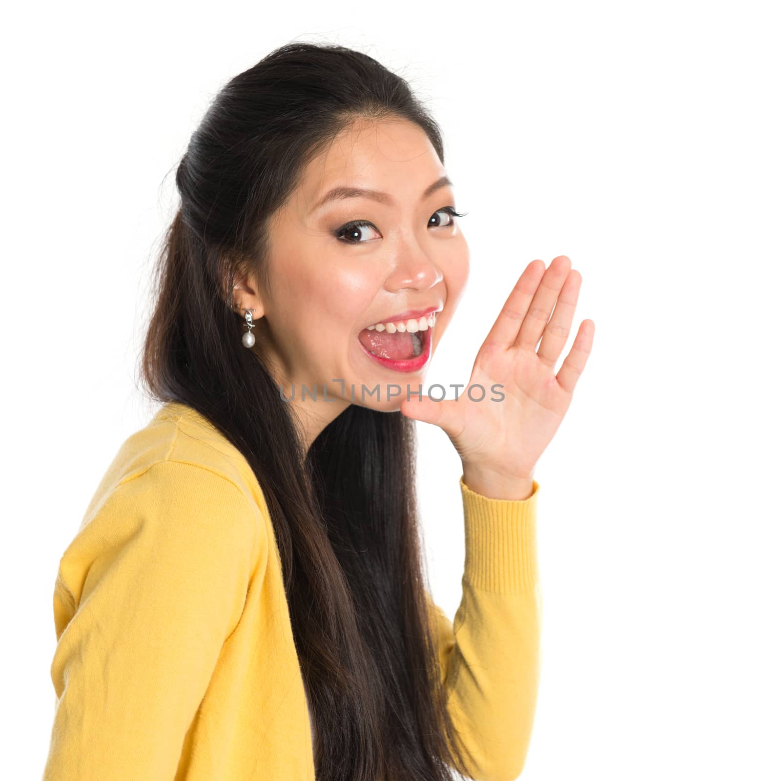 Asian woman holding hand beside her cheek and shouts an announcement, isolated on white background