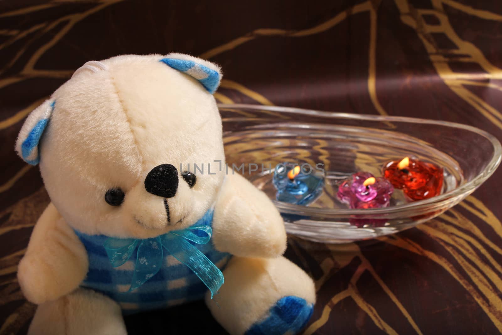 cute teddy bear sitting near floating candle