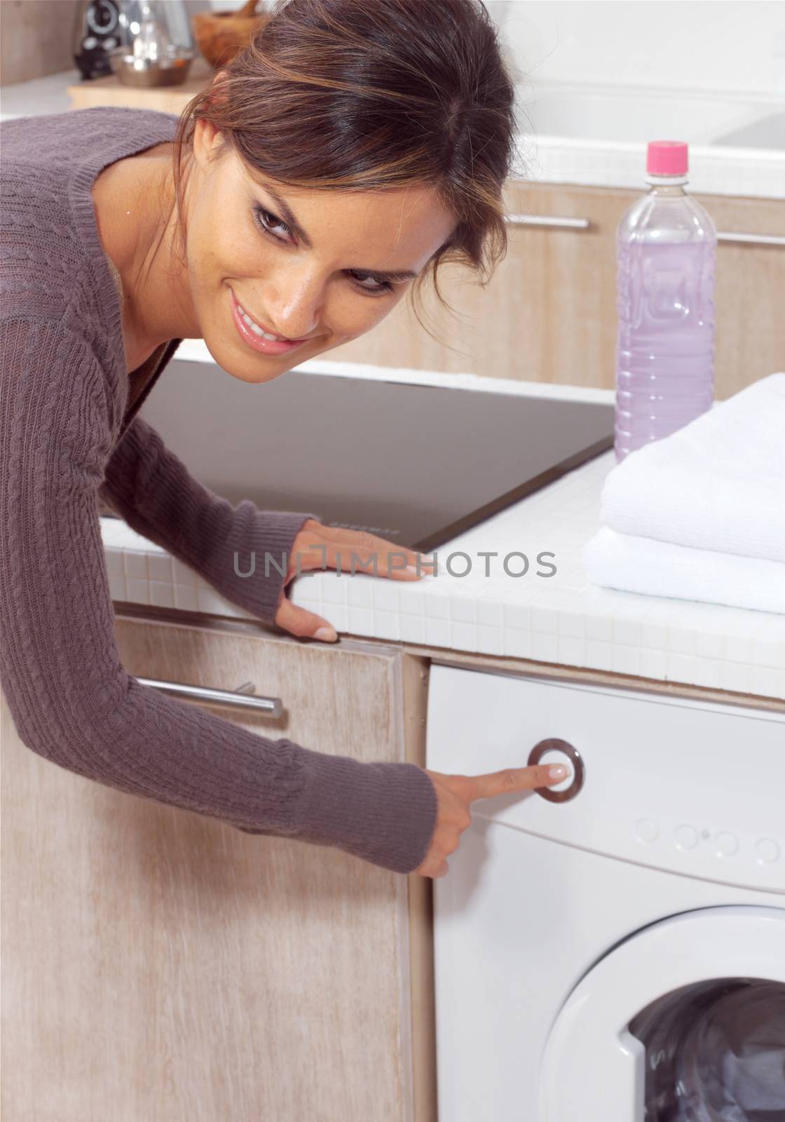 smiling woman pressing a button on her washing machine 