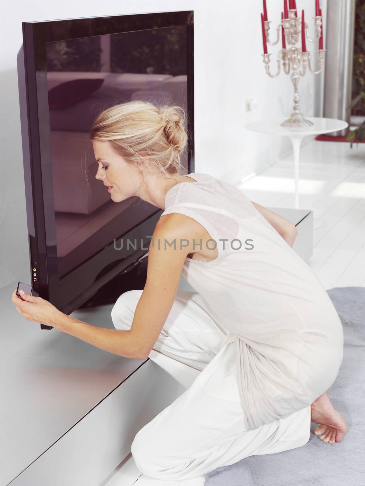 Beautiful blond woman sitting near tv and tries to connect compact chip