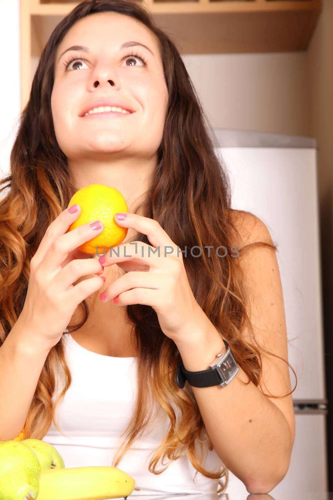 A young adult woman with fruits in the kitchen.