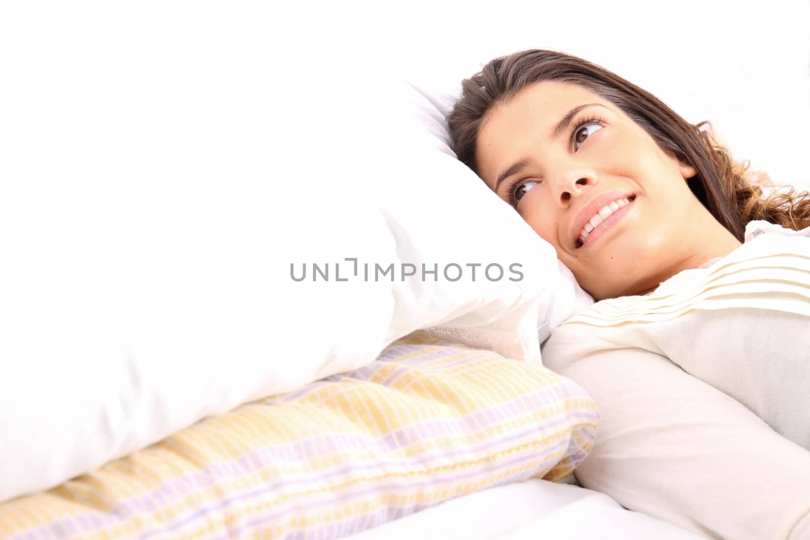 A young girl laying in bed and smiling

