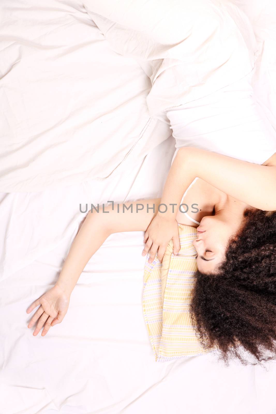 A young latin woman lying down in bed.