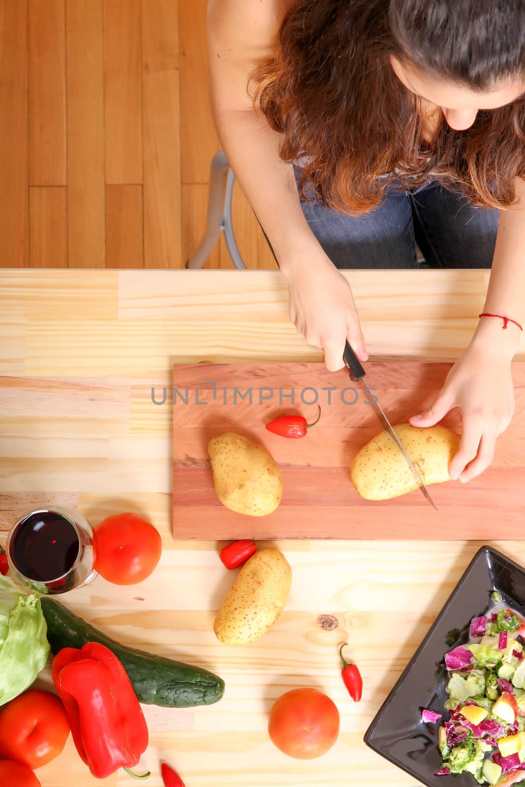 A young woman cutting vegetables ion the kitchen.