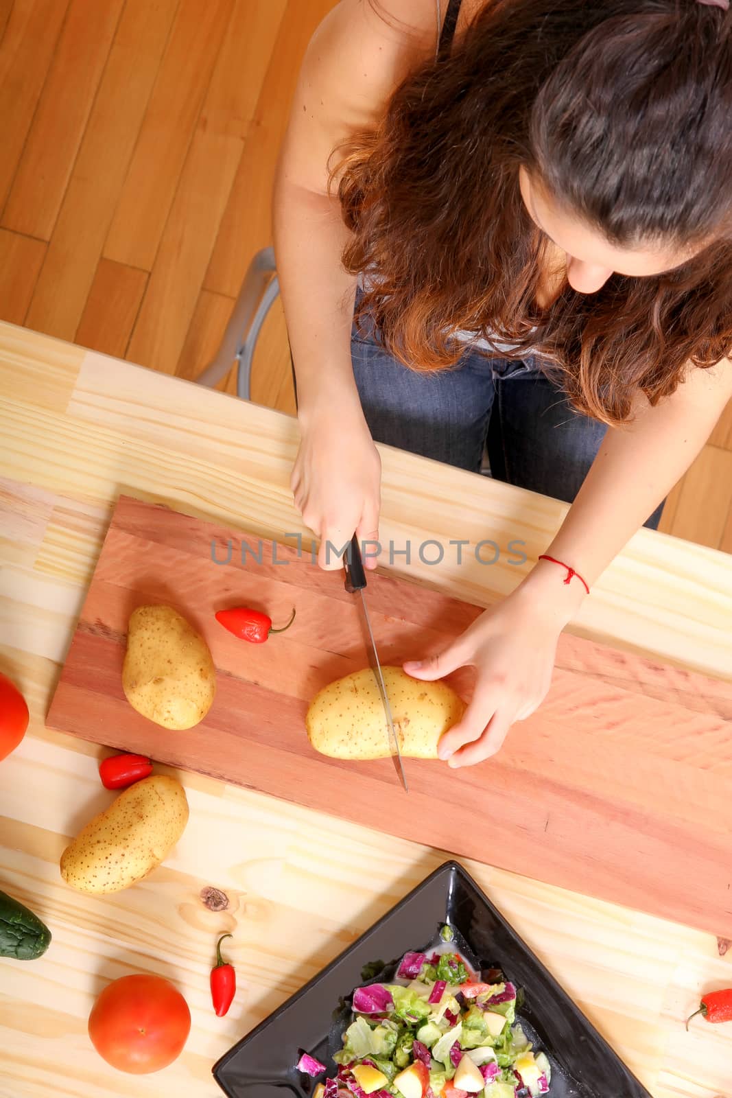 A young woman cutting vegetables ion the kitchen.