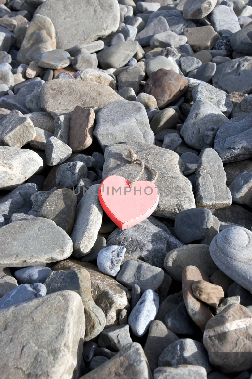 single red hot wooden love heart on a pebble beach in Ireland
