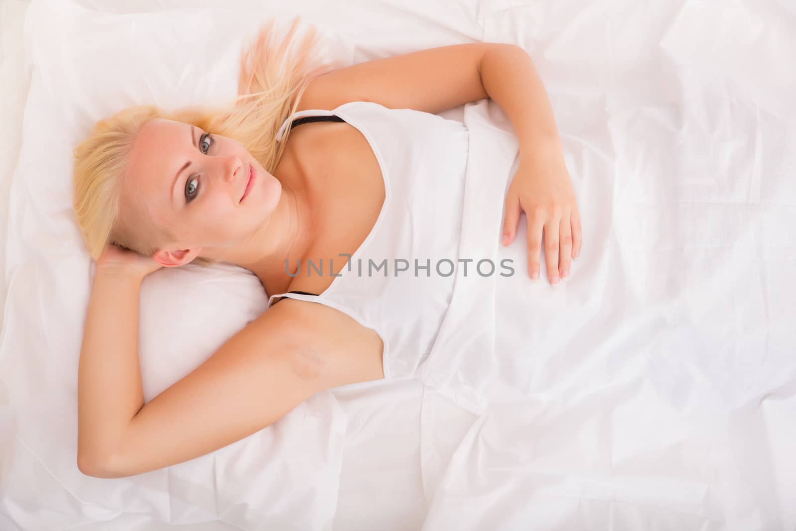 Portrait of a blonde girl lying in a bed.