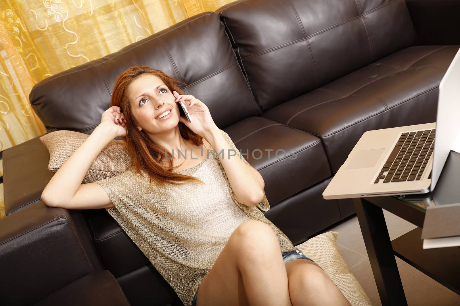 A young adult woman receiving a phone call while relaxing at home.