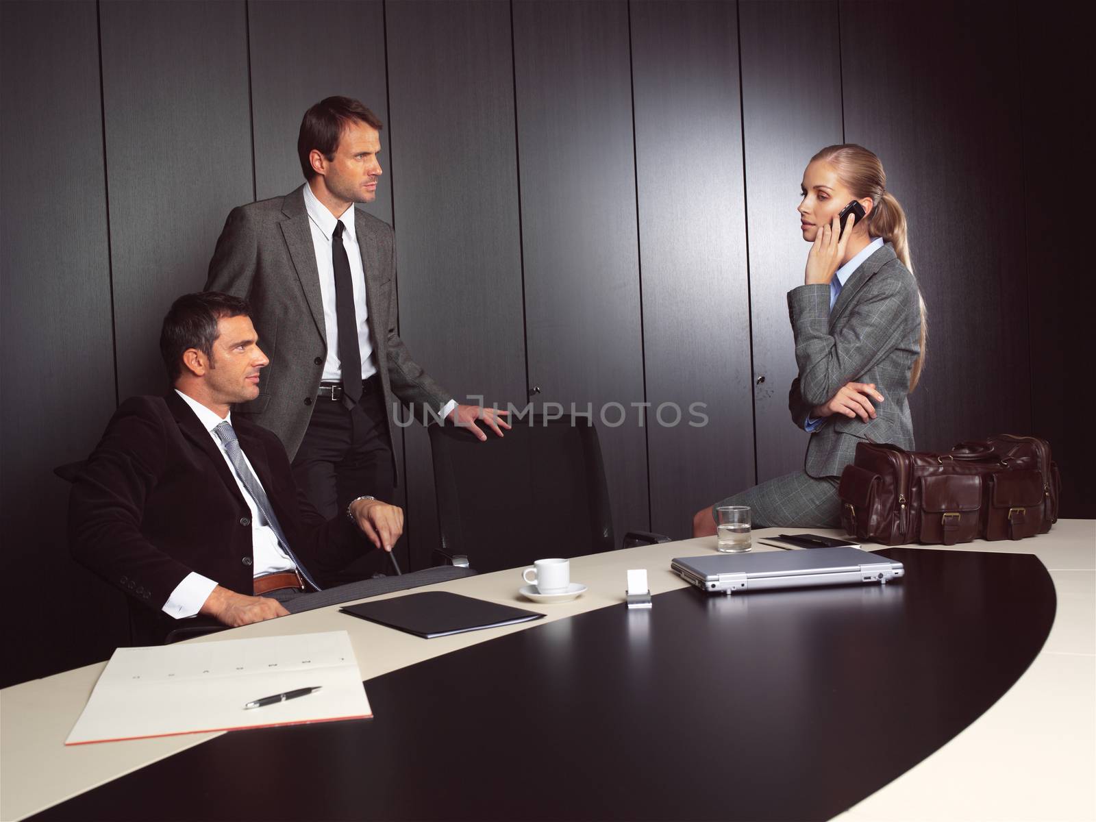 businessman explaining to businesswoman at office sitting on table talking on mobile