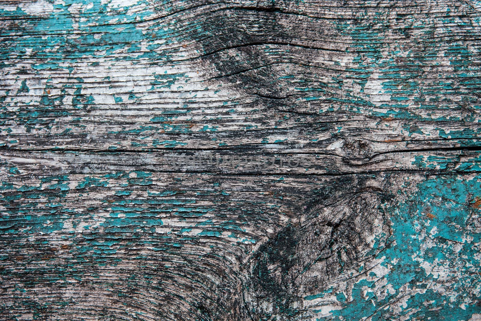 Old wooden plank with the remains of cracked blue paint 