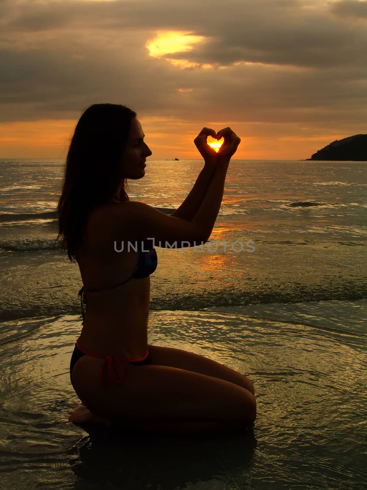 Young woman shaping heart with her hands at sunset, Langkawi island, Malaysia, Southeast Asia