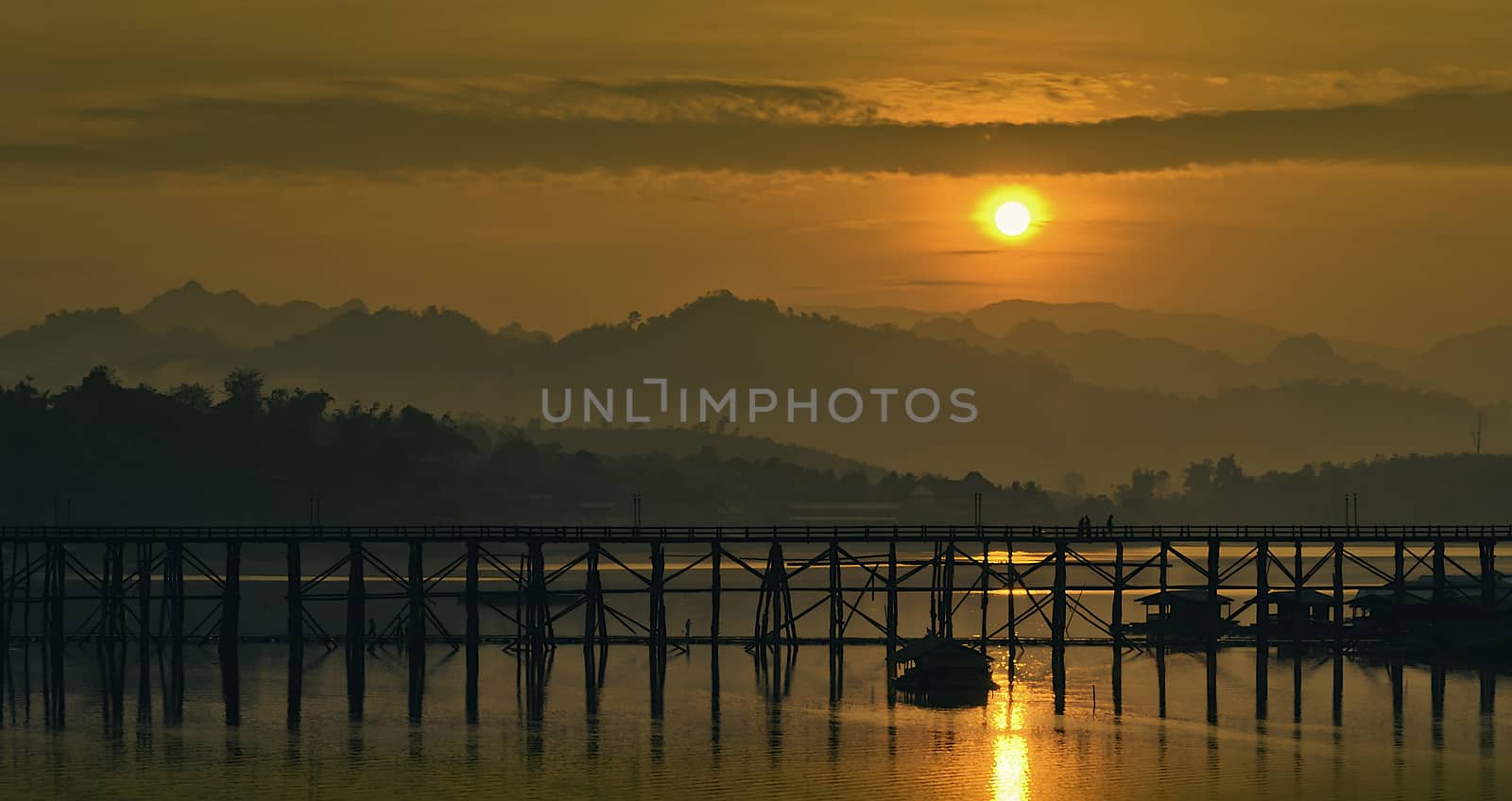 The sun's rising in the morning behind the wooden bridge.