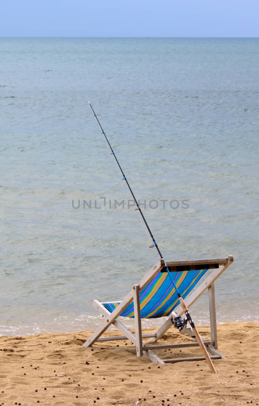 Fishing rod is placed beside the chair beach.