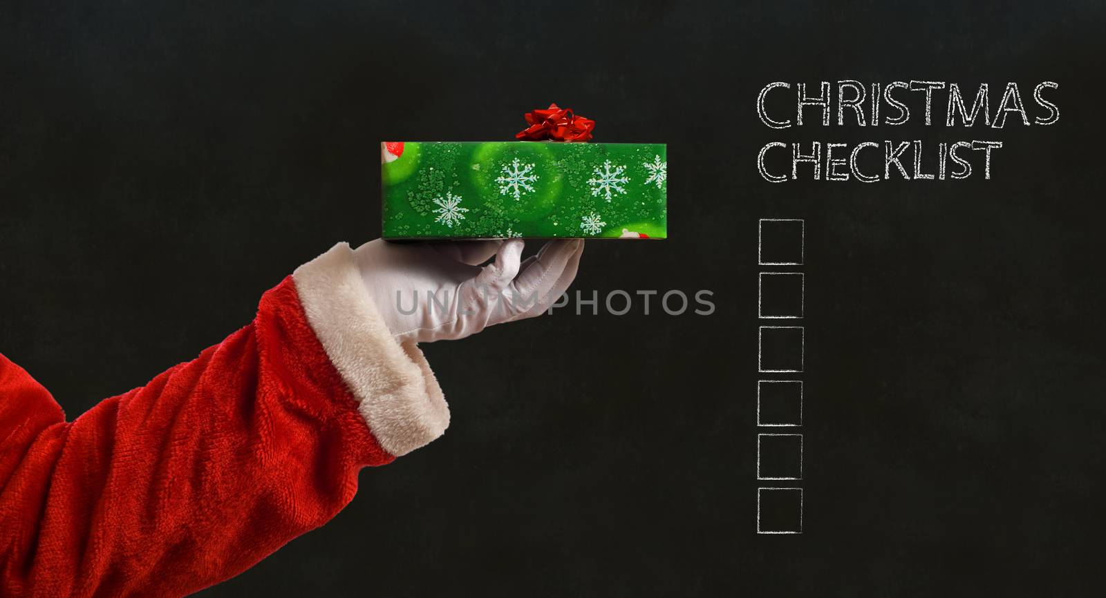 Santa Claus Father Christmas hand with wrapping paper present on blackboard checklist background