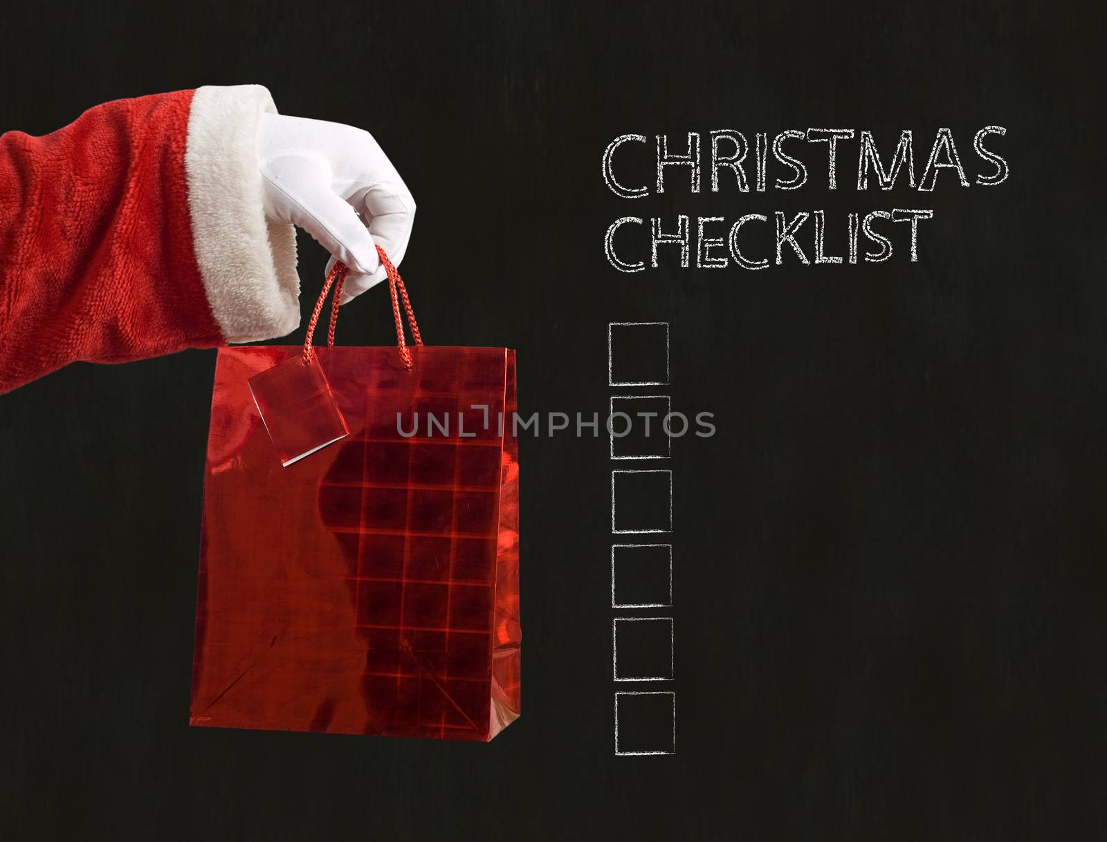 Father Christmas hand holding a red present on blackboard background with checklist