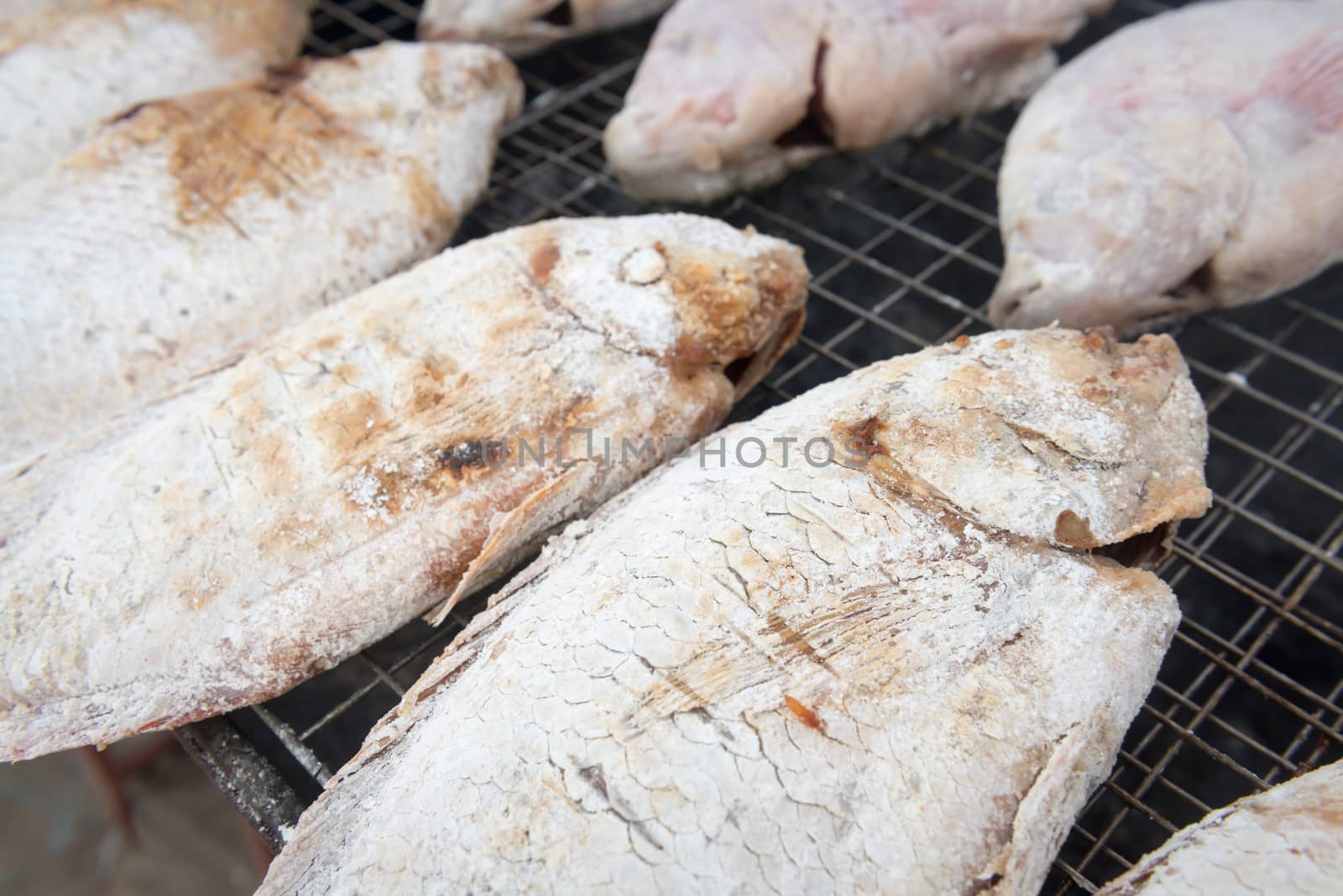 Grilling whole fish in salt on campfire BBQ grate