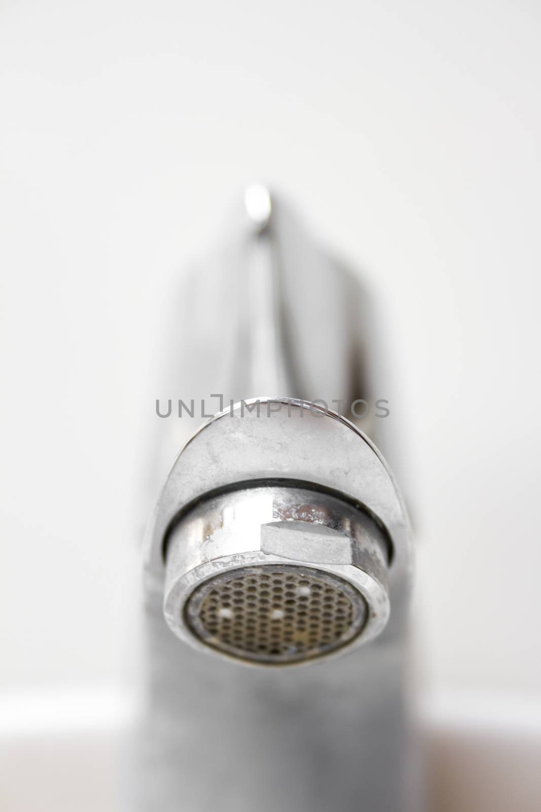 Front view of modern style dirty faucet closeup view on white tiles background with small depth of field