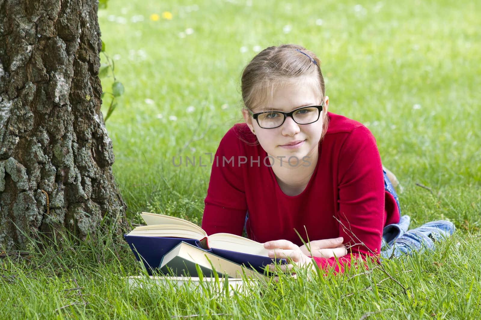Young girl reading book in park in spring day