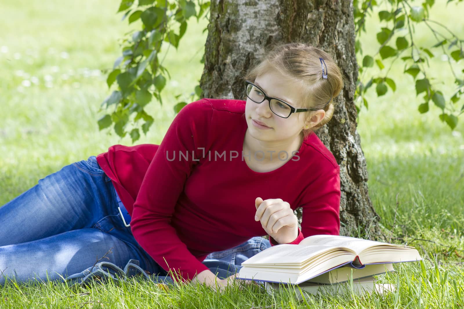 Young girl reading book in park in spring day