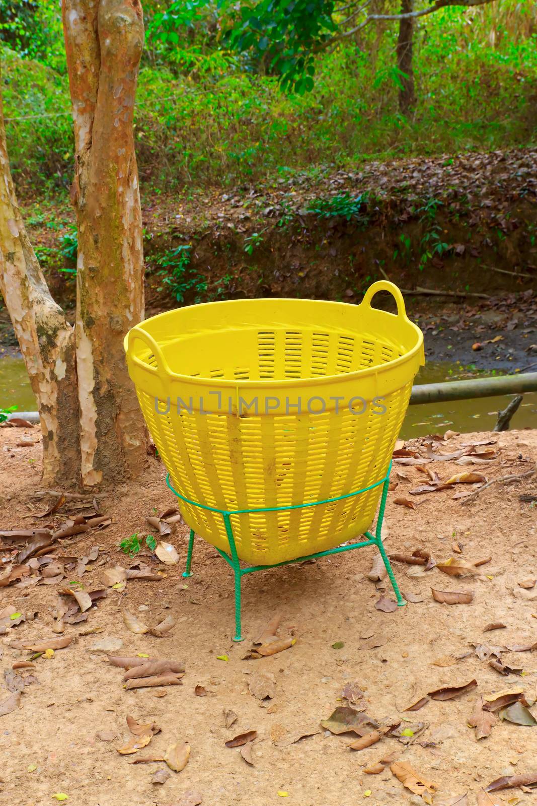 A yellow trash is in the garden.