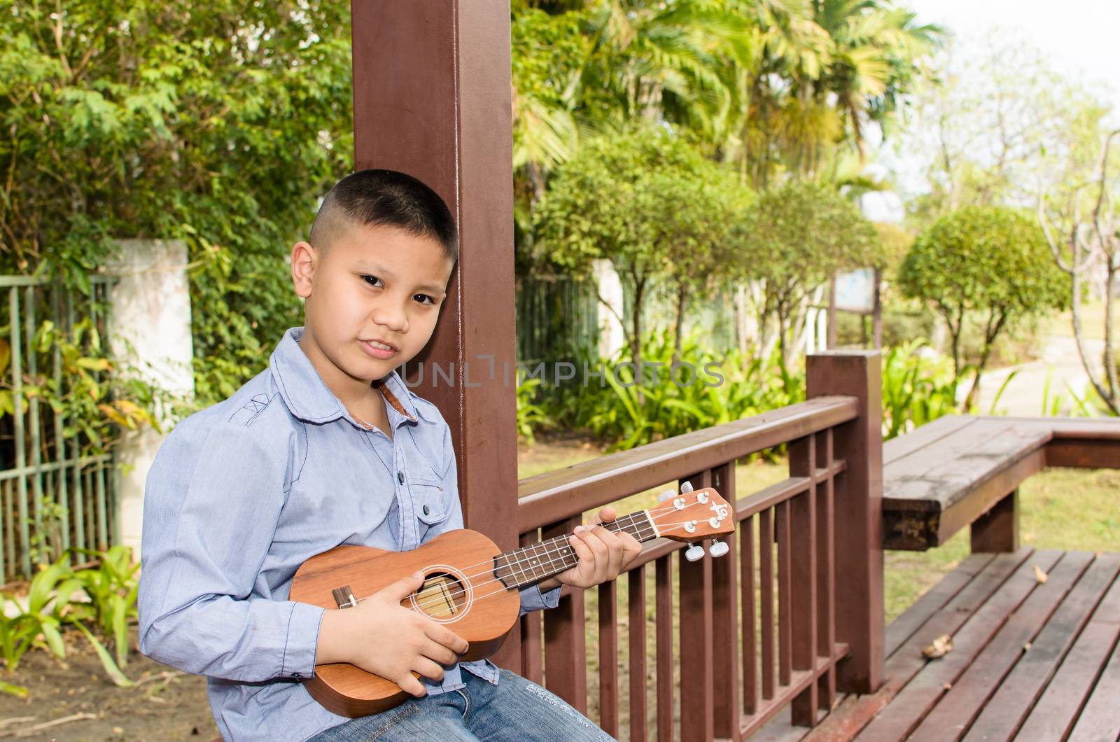 The boy playing the ukulele in the garden.