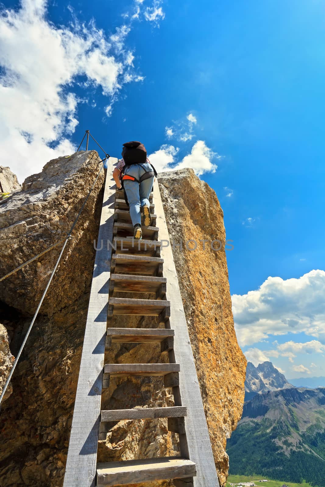 hiker on a big wooden ladder in Bepi Zac via ferrata, Trentino, Italy