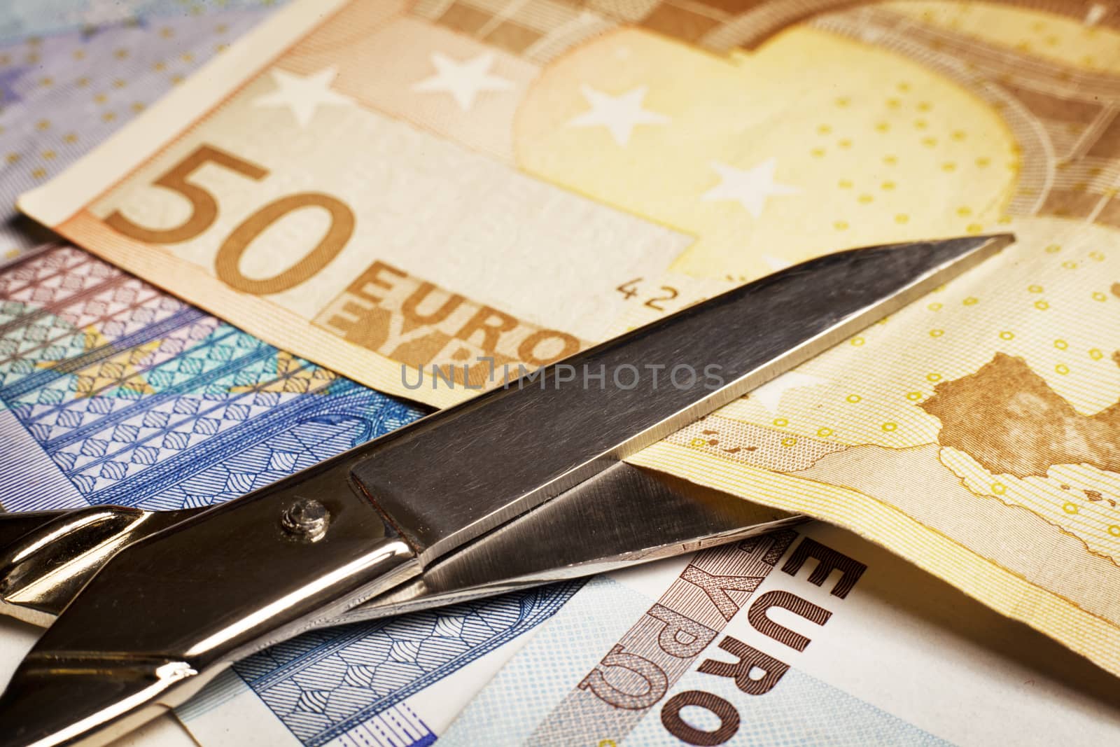 Cutting Costs Idea. Scissors cut a 50 euros Paper Currency.