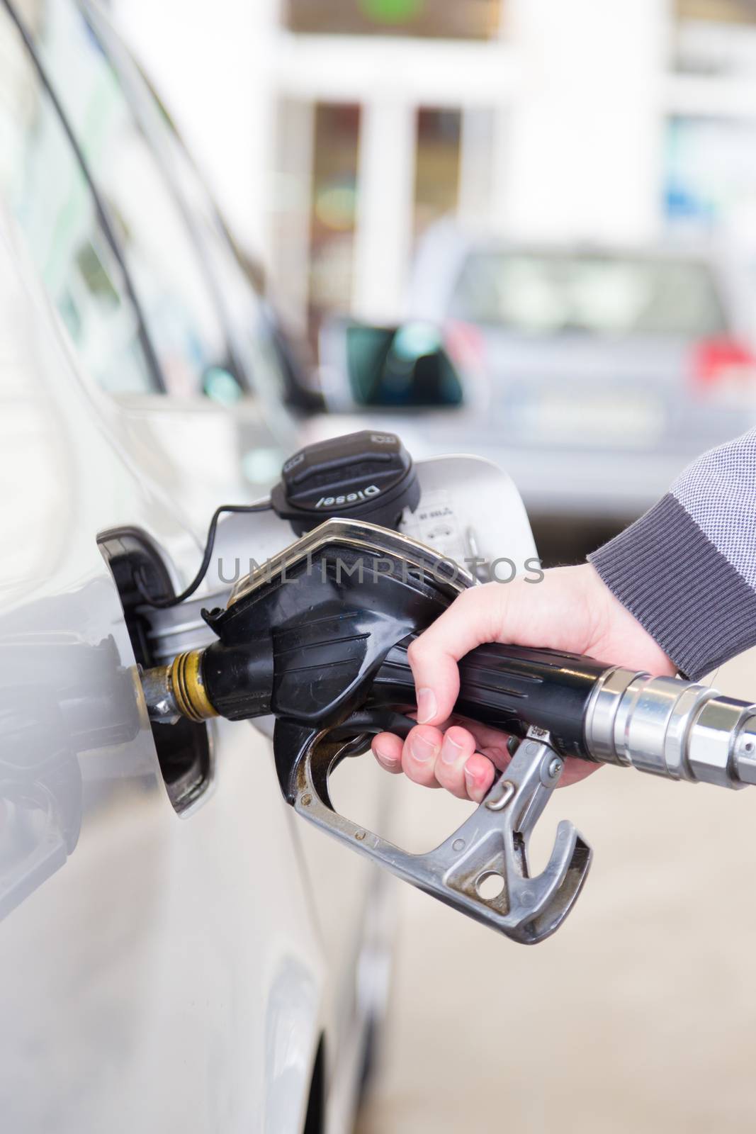 Petrol or gasoline being pumped into a motor vehicle car. Closeup of man pumping gasoline fuel in car at gas station.