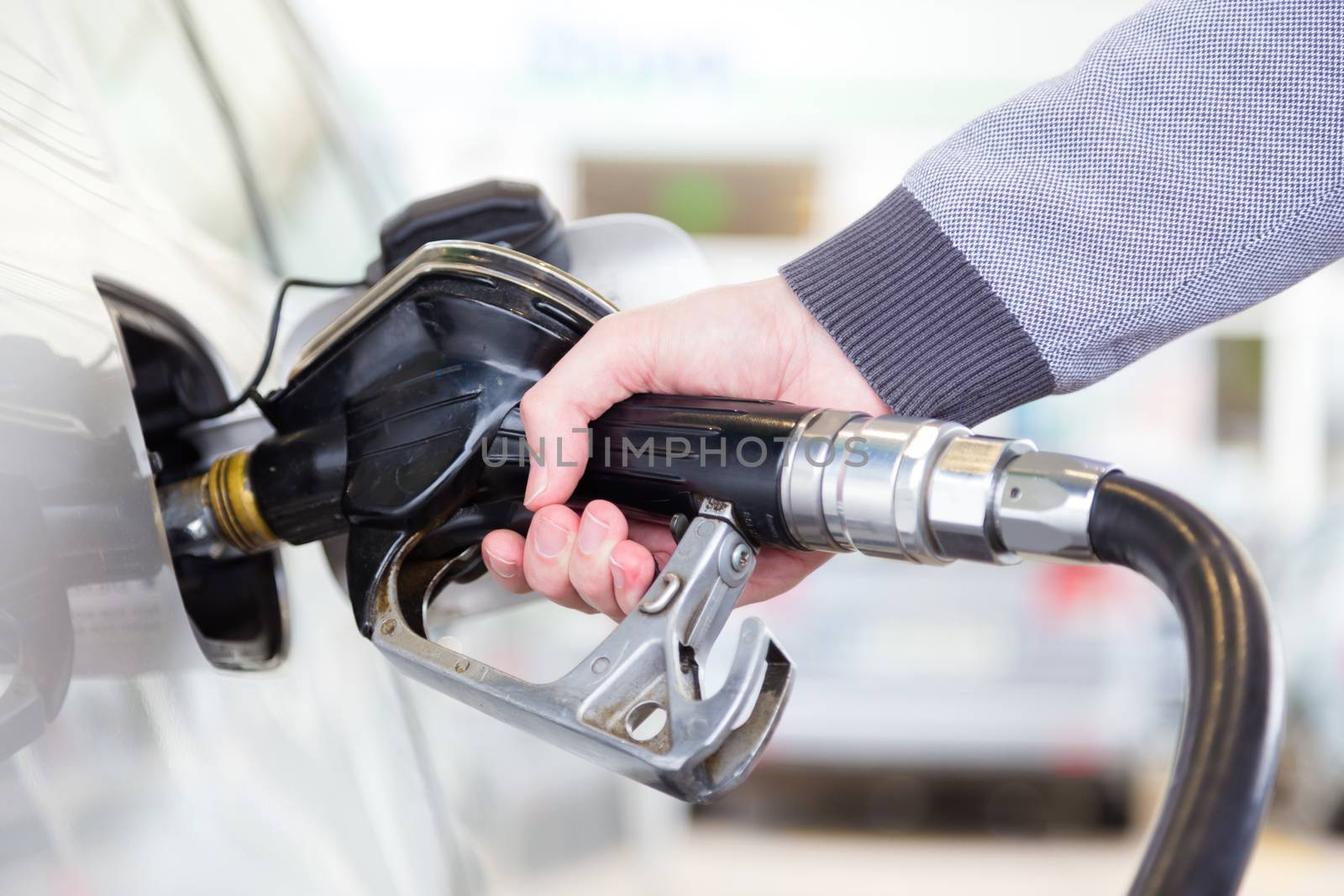 Petrol or gasoline being pumped into a motor vehicle car. Closeup of man pumping gasoline fuel in car at gas station.