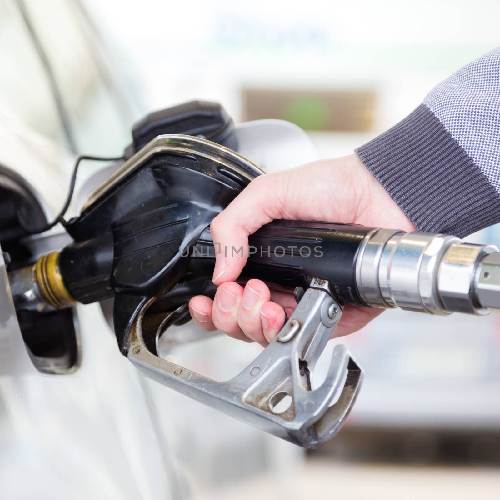 Petrol or gasoline being pumped into a motor vehicle car. Closeup of man pumping gasoline fuel in car at gas station.