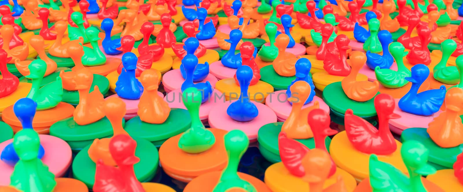 Many colorful rubber ducks floating in water.