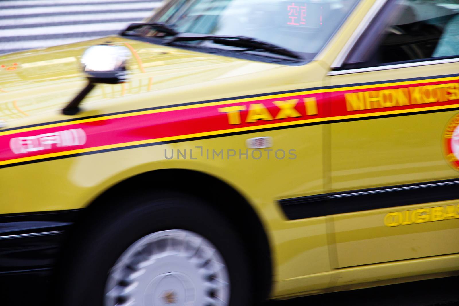 Tokyo, Japan - April, 16 2014: A japanese yellow taxi stopped in front of the zebra crossing.