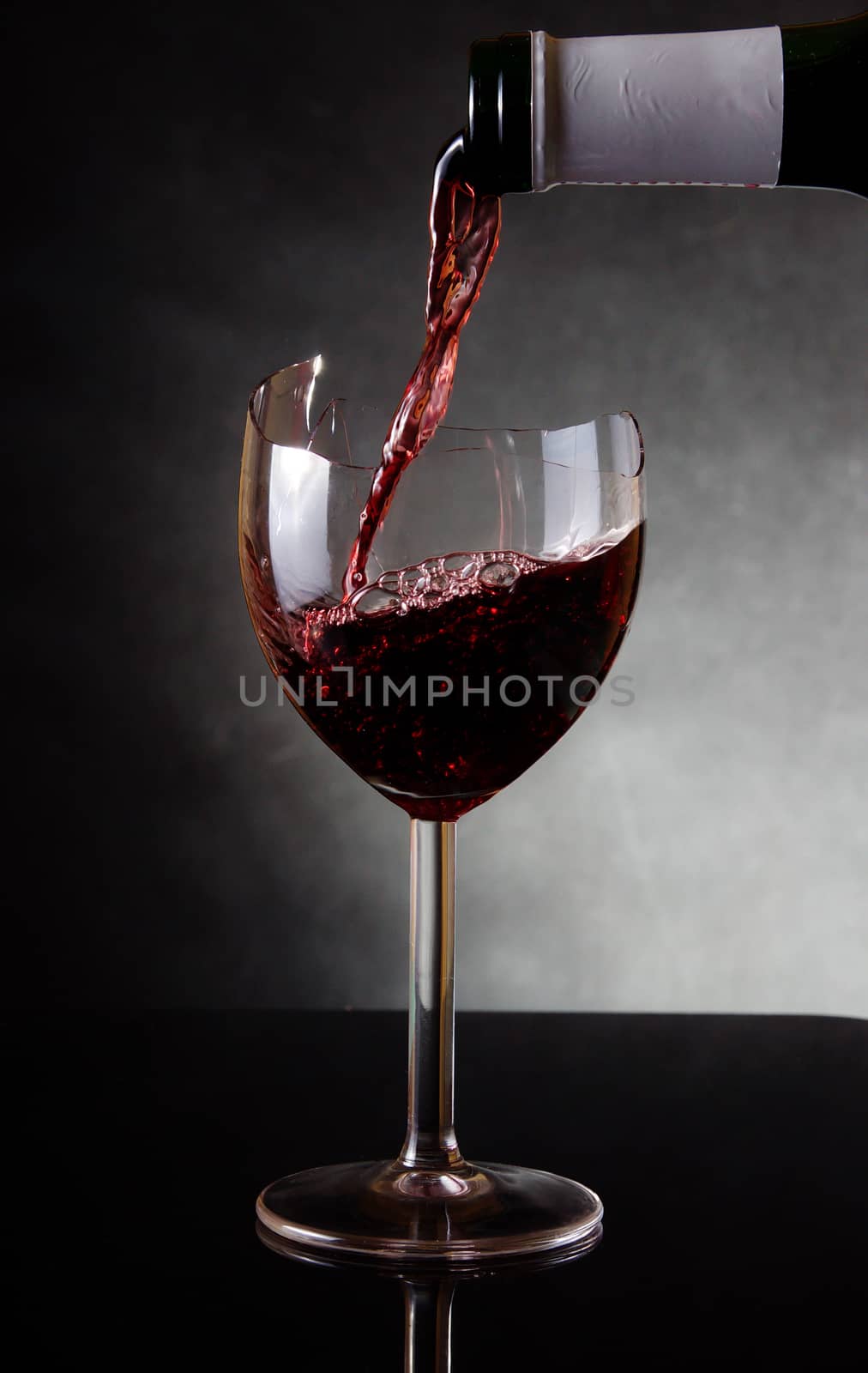 Pouring red vine into a broken glass