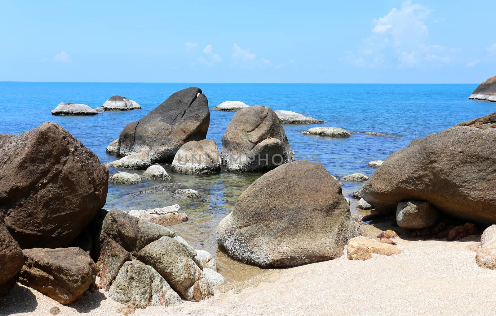 Stones on the beach by the sea on a background of blue sky