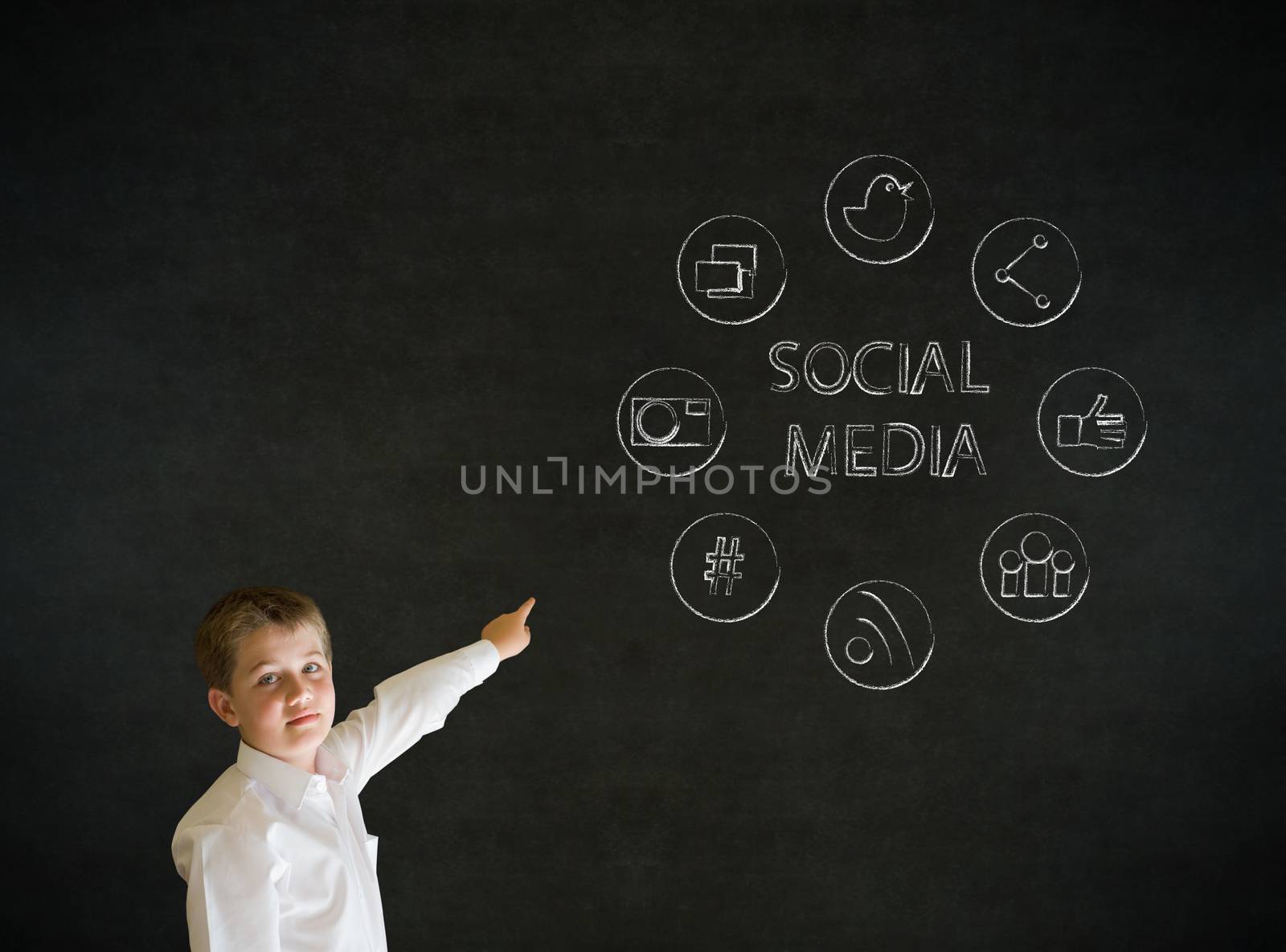 Pointing boy dressed up as business man with social media icons on blackboard background