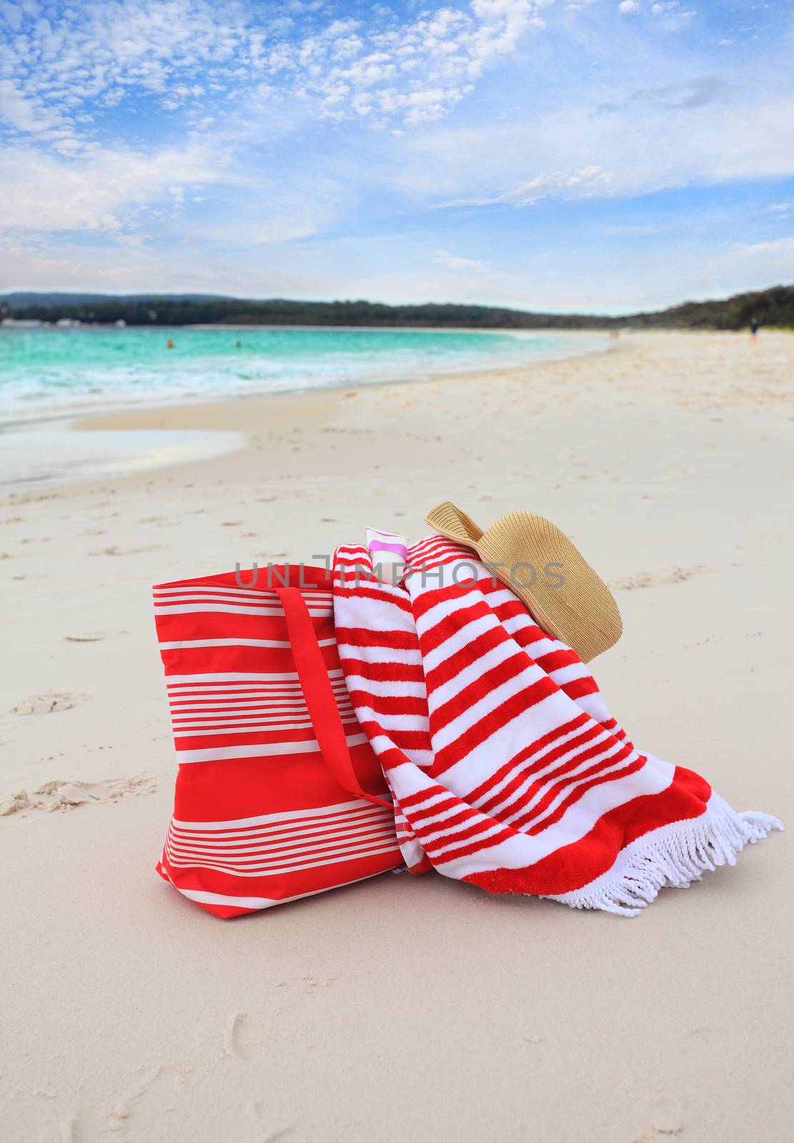 Beach bag, beach towel, hat and sunscreen on the sandy seashore