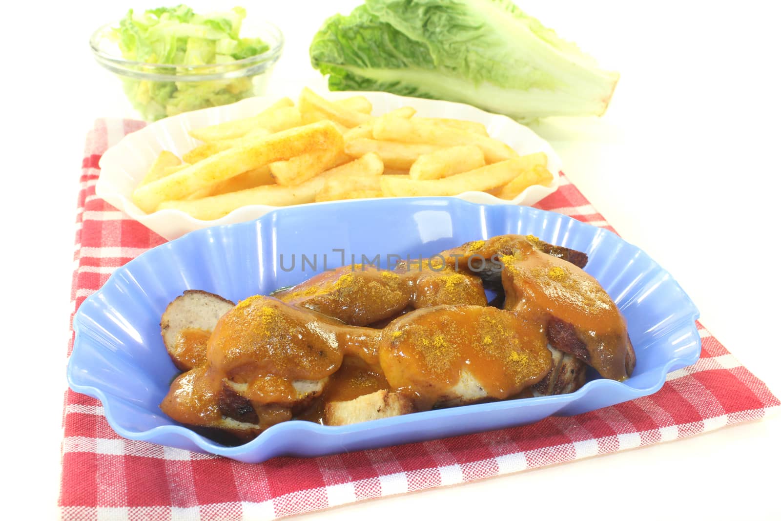 Currywurst with french fries on a napkin before light background