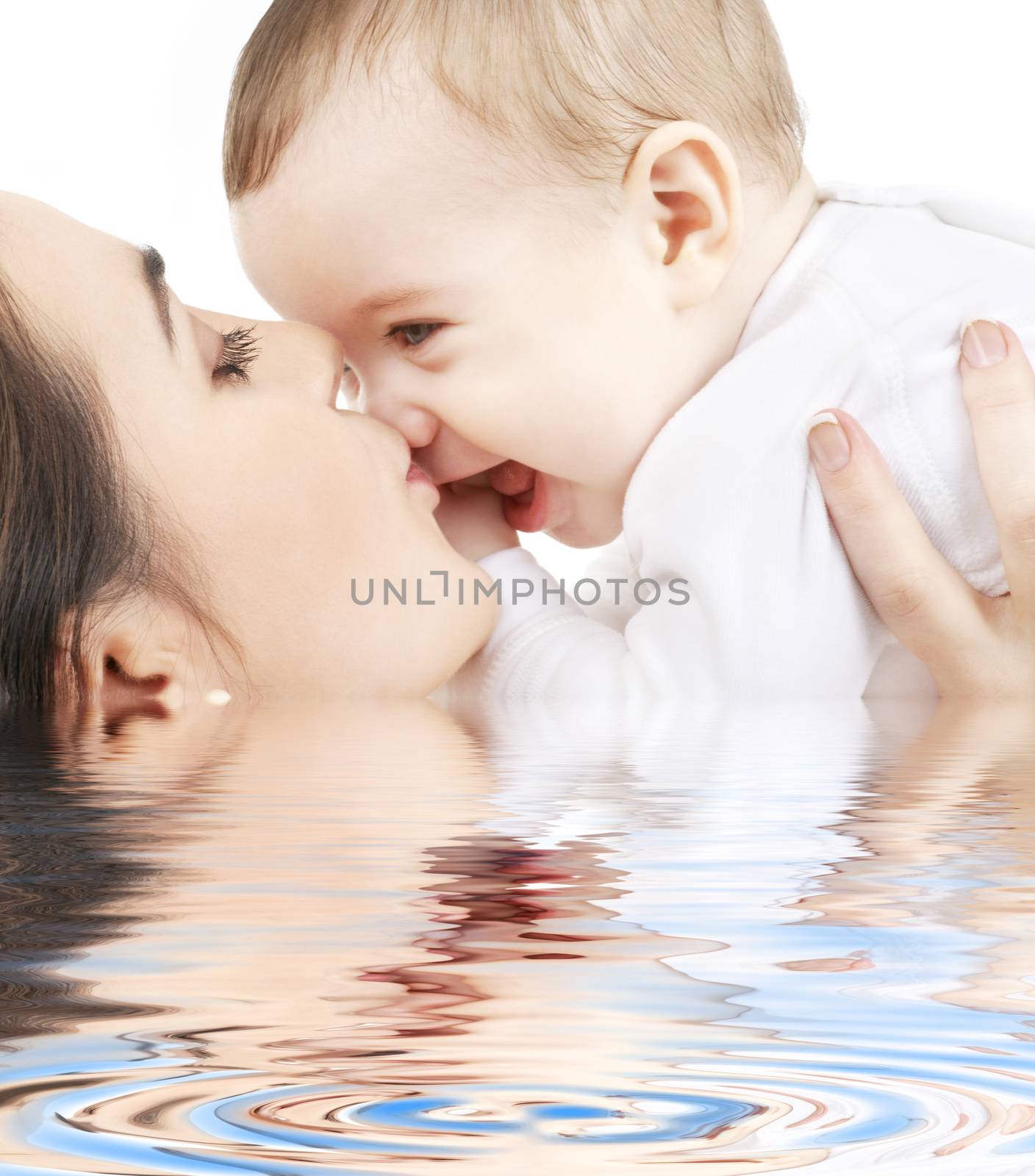 happy mother kissing baby boy in water by dolgachov