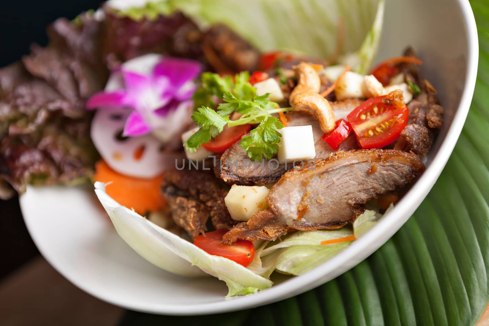 Thai Salad with Crispy Duck and fresh green mango tomatoes and cashew nuts on a bed of lettuce.