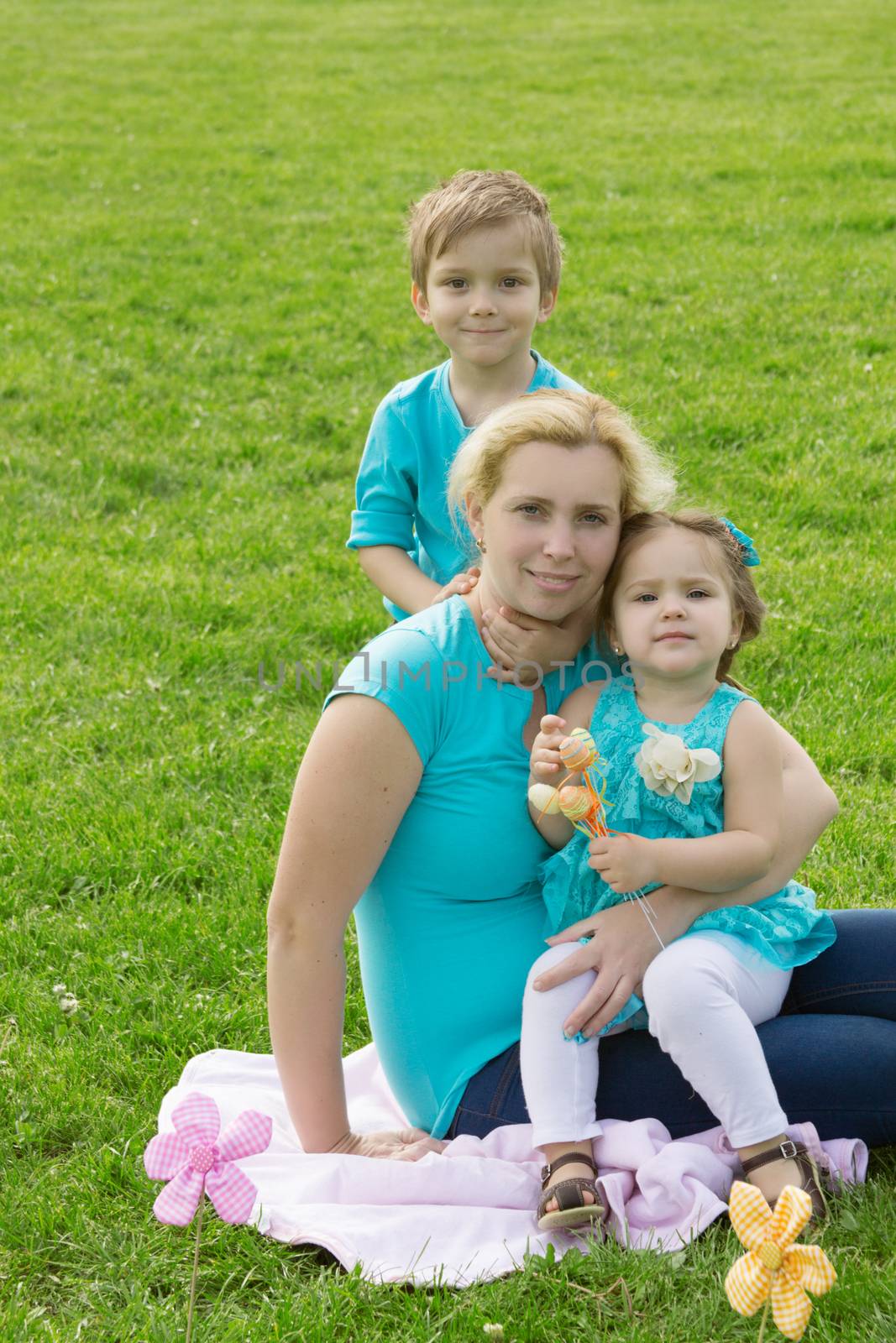 Lovely mother and little boy and girl in green grass