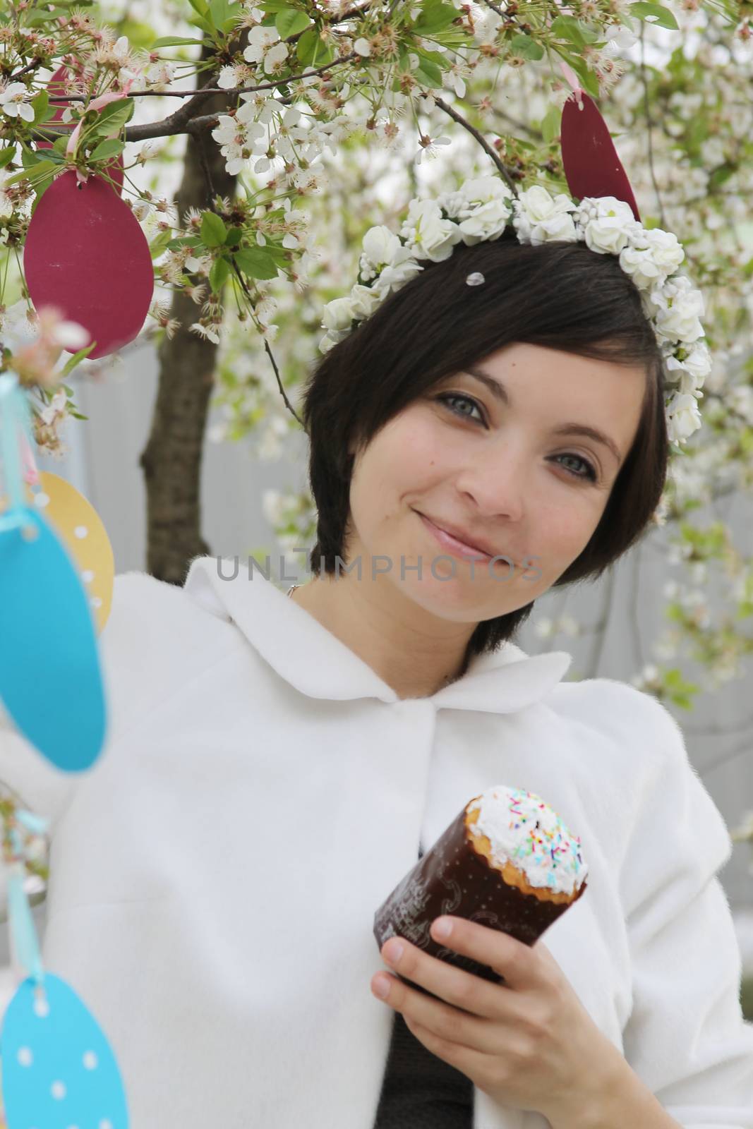 Sensual woman with wreath and Easter cake among spring garden