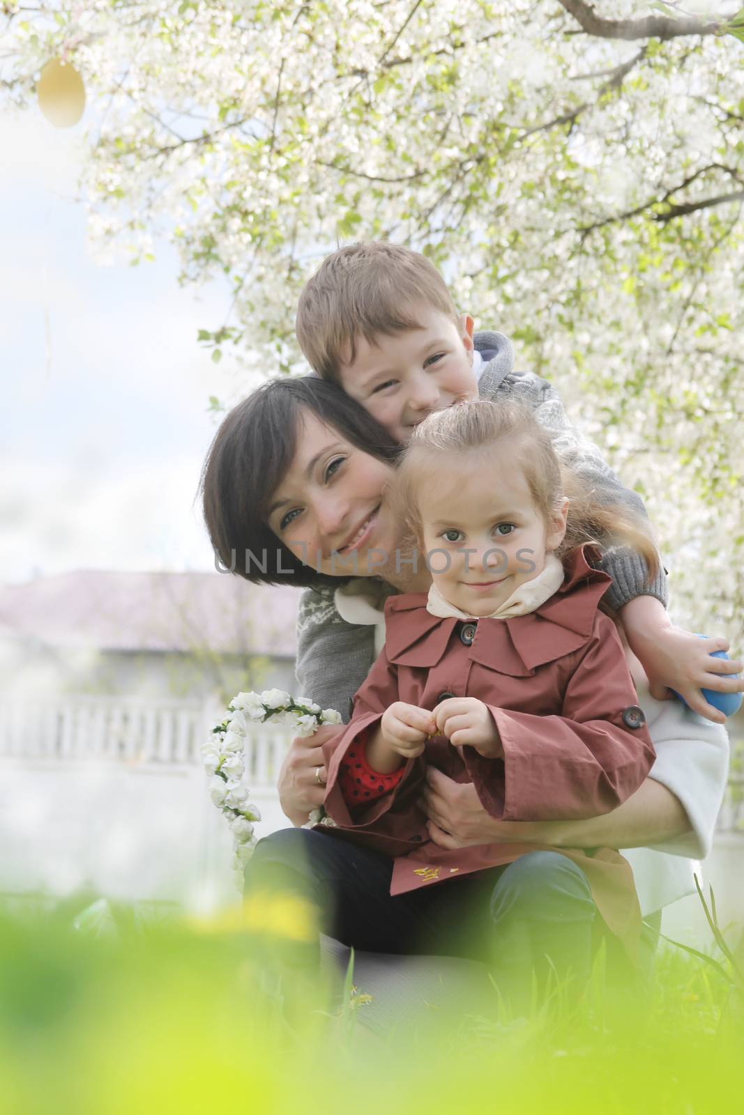 Happy mother and two children hugging among blooming garden